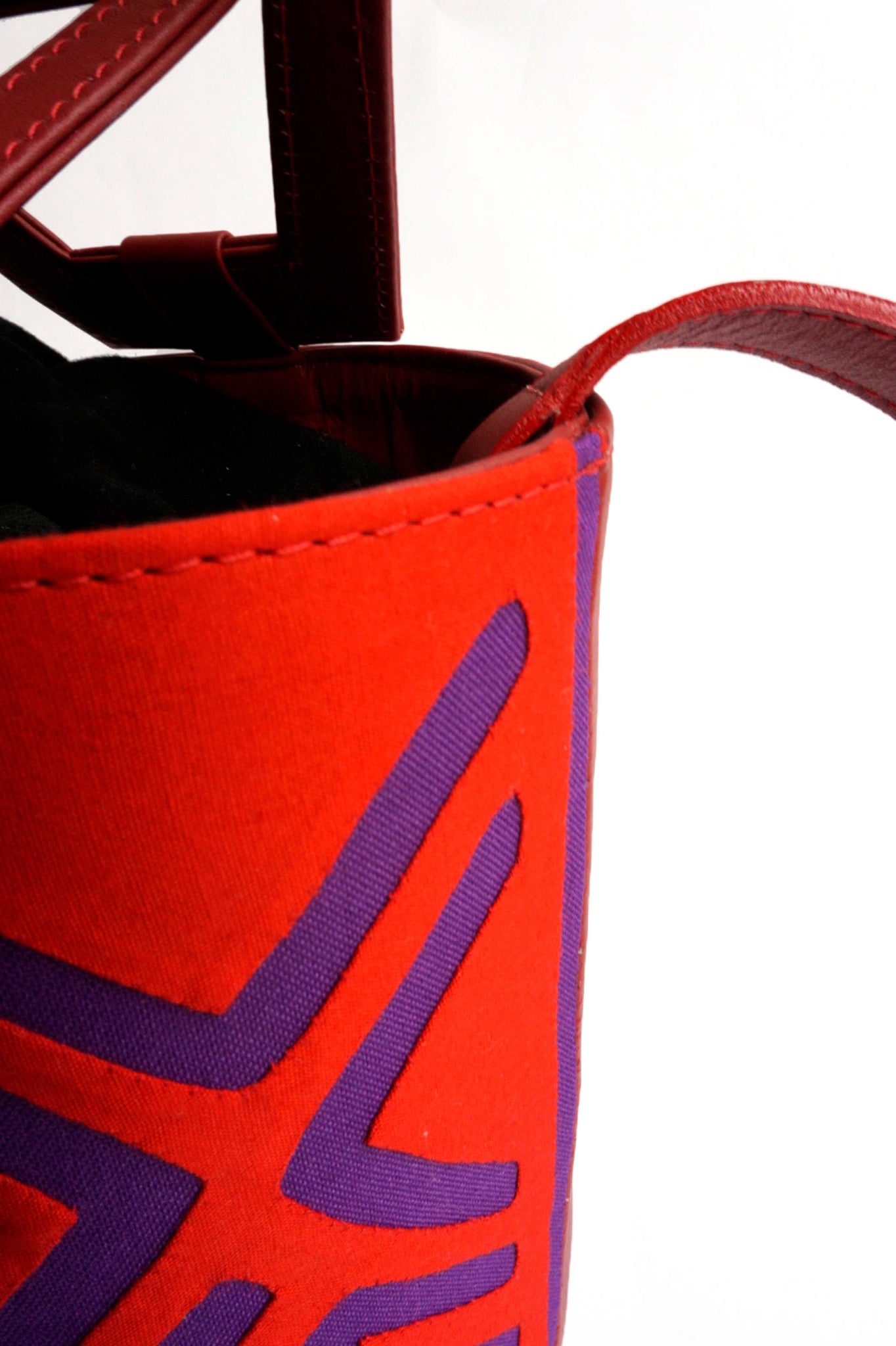Nabba Tote by Fe Handbags. Handmade in Colombia. Nabba Bag featuring a bright denim Mola made by indigenous people from the Gunadule Tribe. Polished gunmetal gold plated metal fastenings. Detachable leather strap for alternative styling. Color red. 100% calfskin leather.