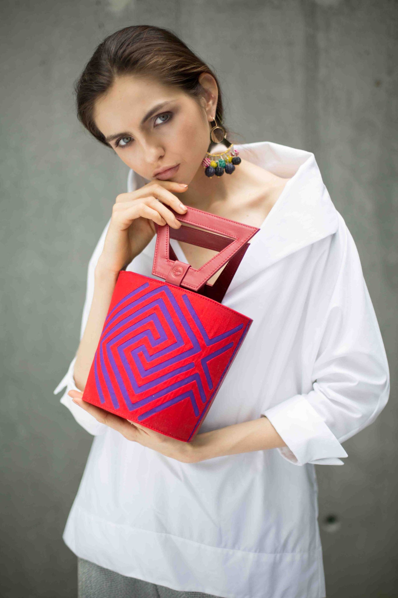 Nabba Tote by Fe Handbags. Handmade in Colombia. Nabba Bag featuring a bright denim Mola made by indigenous people from the Gunadule Tribe. Polished gunmetal gold plated metal fastenings. Detachable leather strap for alternative styling. Color red. 100% calfskin leather.