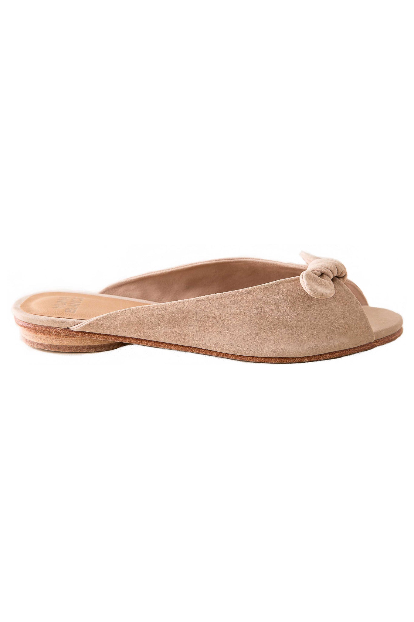Huma Blanco Spring 2018 Nolita Mule. Knotted suede strap provides an impeccable finish for this handcrafted open toe mule slide sandal. Open toe slide in soft suede with bowtie detail. Feminine and easy to style with everything from dresses to denim. Made by hand in Peru. Color nude. Suede upper, leather insole, leather lining, leather sole, and wood heel with rubber sole. Leather insole with leather heel. Heel height: 0.5". Sizes 37 38 39.