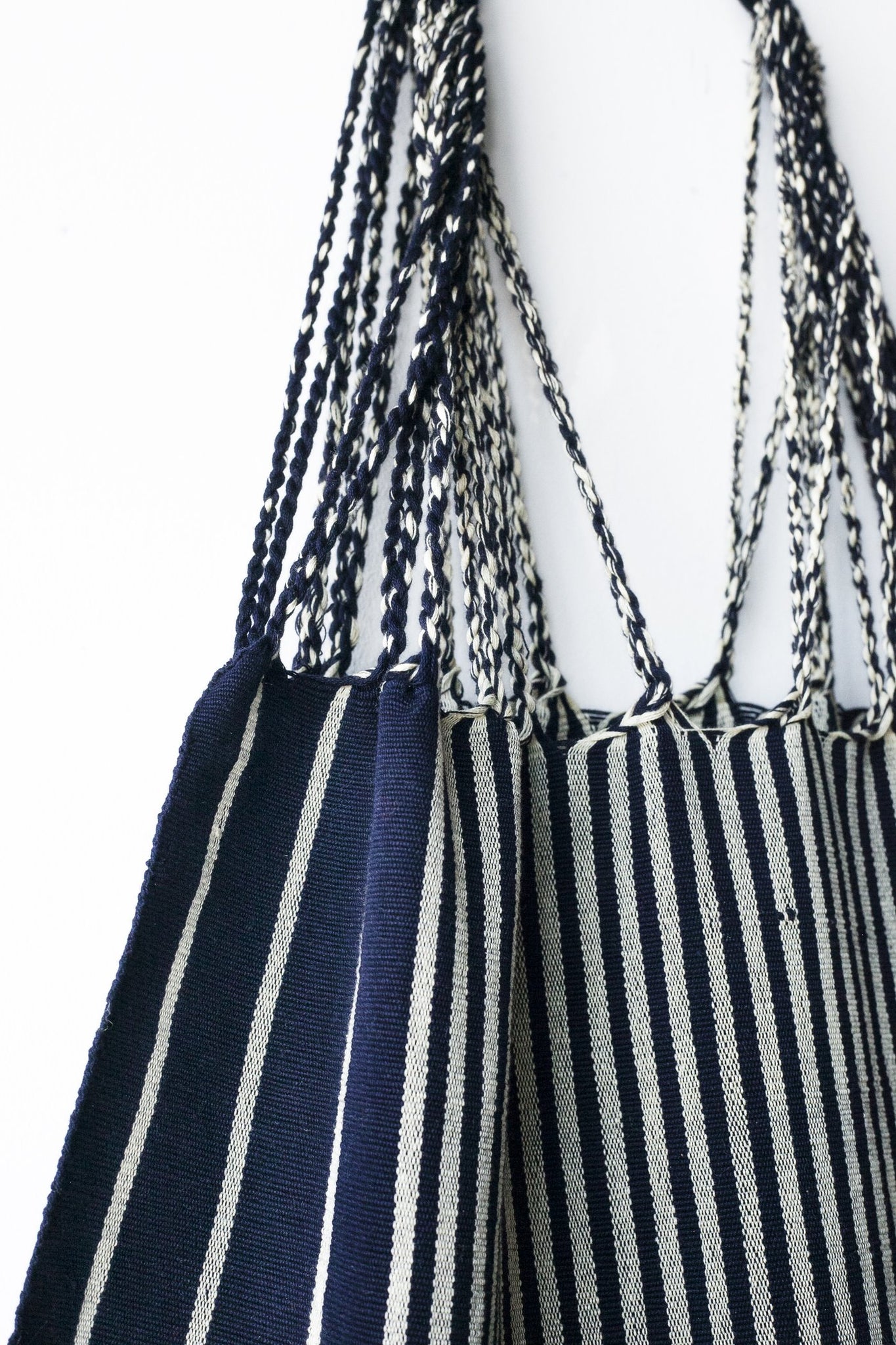 Navy Hammock Bag by The Global Trunk. Handwoven in Mexico. These little tote bags are perfect for going to the market or the beach! Each Hammock Bag is handwoven on a back-strap loom by artisans in the highland region of Chiapas, Mexico. Color navy. 100% cotton.
