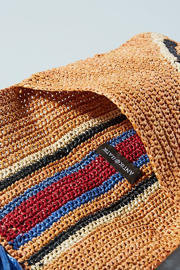 Antik Batik Spring 2018 Rufo Clutch. Woven raffia clutch with stripe pattern and tassel detail. Unlined. 8 inches by 10 inches. Color Brown. 100% raffia. One Size.